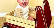 Leo joined the competition — help win amazing prizes! baby, carpet, child, clothing, cute, face, fun, happy, indoor, person, play, radio_flyer, red, sitting, sleeves, smiling, toy, wagon, white, wood