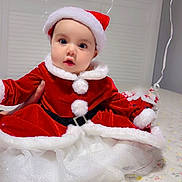Parry joined the competition — help win amazing prizes! baby, child, santa_hat, christmas_outfit, red_clothing, white_fur_trim, bed, floral_bedspread, indoors, window, curious, cute, holiday, festive, tulle_skirt, person, portrait, holiday_costume, celebration, smiling