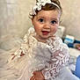 baby, child, smiling, dress, lace, headband, flower, white, cute, portrait, sitting, happy, indoor, soft_focus, infant, young_child, face, hand, eyes, clothing