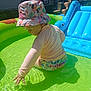 toddler, child, swimwear, bucket_hat, inflatable_pool, water, outdoor, sunlight, summer, play, blue_inflatable, dinosaur, person, table, chair, adult, backyard, grass, footwear, curious