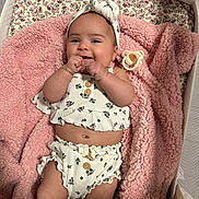 Bellamy is registered to the contest to win money with this photo: baby, infant, smiling, blanket, pink, headband, baby_clothes, bassinet, pacifier, cute, happy, lying_down, skin, fingers, wrinkled_blanket, wood, cute_outfit, baby_accessory, indoors, portrait