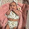 baby, infant, smiling, blanket, pink, headband, baby_clothes, bassinet, pacifier, cute, happy, lying_down, skin, fingers, wrinkled_blanket, wood, cute_outfit, baby_accessory, indoors, portrait