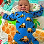 Joseph joined the competition — help win amazing prizes! baby, child, onesie, blue_clothing, construction_vehicle_pattern, play_mat, pillow, toy, smiling, happy, indoor, infant, face, arms_outstretched, colorful, patterned, cute, lying_down, soft_toys, playtime