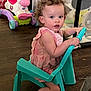 toddler, child, curly_hair, pink_dress, plastic_chair, toy_unicorn, playpen, wooden_floor, indoor, barefoot, holding, seated, furniture, colorful, young_child, cute, curious, play_area, home, girl