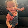 Zuri joined the competition — help win amazing prizes! toddler, child, smiling, curly_hair, denim_overalls, pink_shirt, indoor, couch, black_leather, happy, cute, portrait, baby, person, expression, hand, feet, earrings, polka_dot, clothing