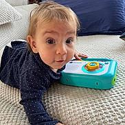 Leonie a rejoint le concours — aidez-le/la à gagner de superbes lots ! baby, child, infant, toy, polka_dot, navy_clothing, blanket, couch, indoor, curious, face, hand, play, texture, portrait, person, home, furniture, expression, toddler