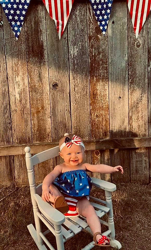 Juliette is registered to the contest to win money with this photo: chair, child, design, flag, flag_of_the_united_states, furniture, happy, headwear, joy, pattern, person, photography, plant, play, product, red, shoe, sitting, summer, toddler