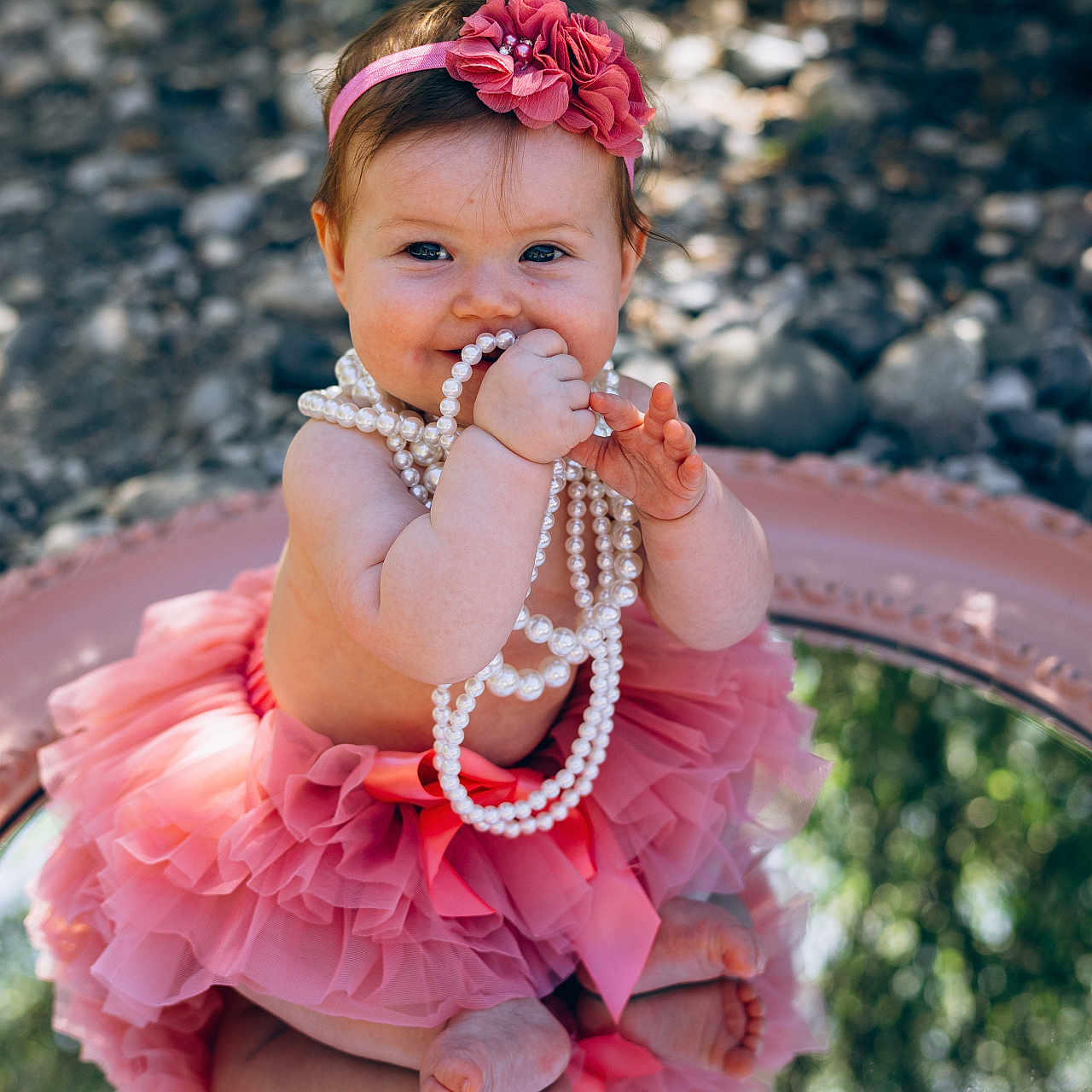 Kaija is registered to the contest to win money with this photo: baby, tutu, pink, headband, flower, pearls, reflection, outdoor, rocks, smiling, cute, child, playful, portrait, sitting, feet, hands, nature, accessory, happy