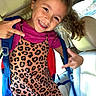 child, girl, smile, happy, leopard_print, dress, backpack, car, seat, window, curly_hair, peace_sign, portrait, casual, daylight, clothing, person, inside, fun, youth