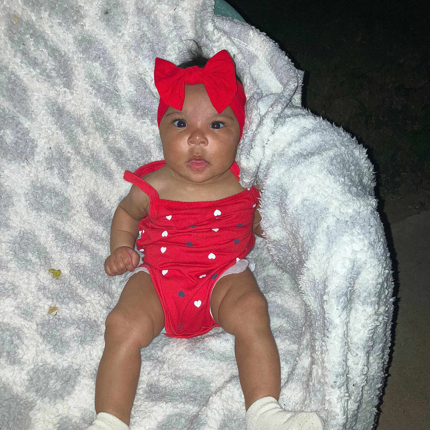 Zariah is registered to the contest to win money with this photo: baby, infant, child, portrait, red_bow, red_outfit, heart_pattern, blanket, fluffy_blanket, socks, sitting, lying_down, wide_eyes, outdoor, night, flash_photography, close_up, adorable, casual_photo, family_photo