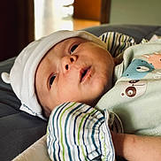 Enzo joined the competition — help win amazing prizes! baby, infant, hat, striped_clothing, blanket, closeup, face, person, cute, sleepwear, lying_down, soft_lighting, indoors, newborn, portrait, apparel, headwear, expression, skin, child