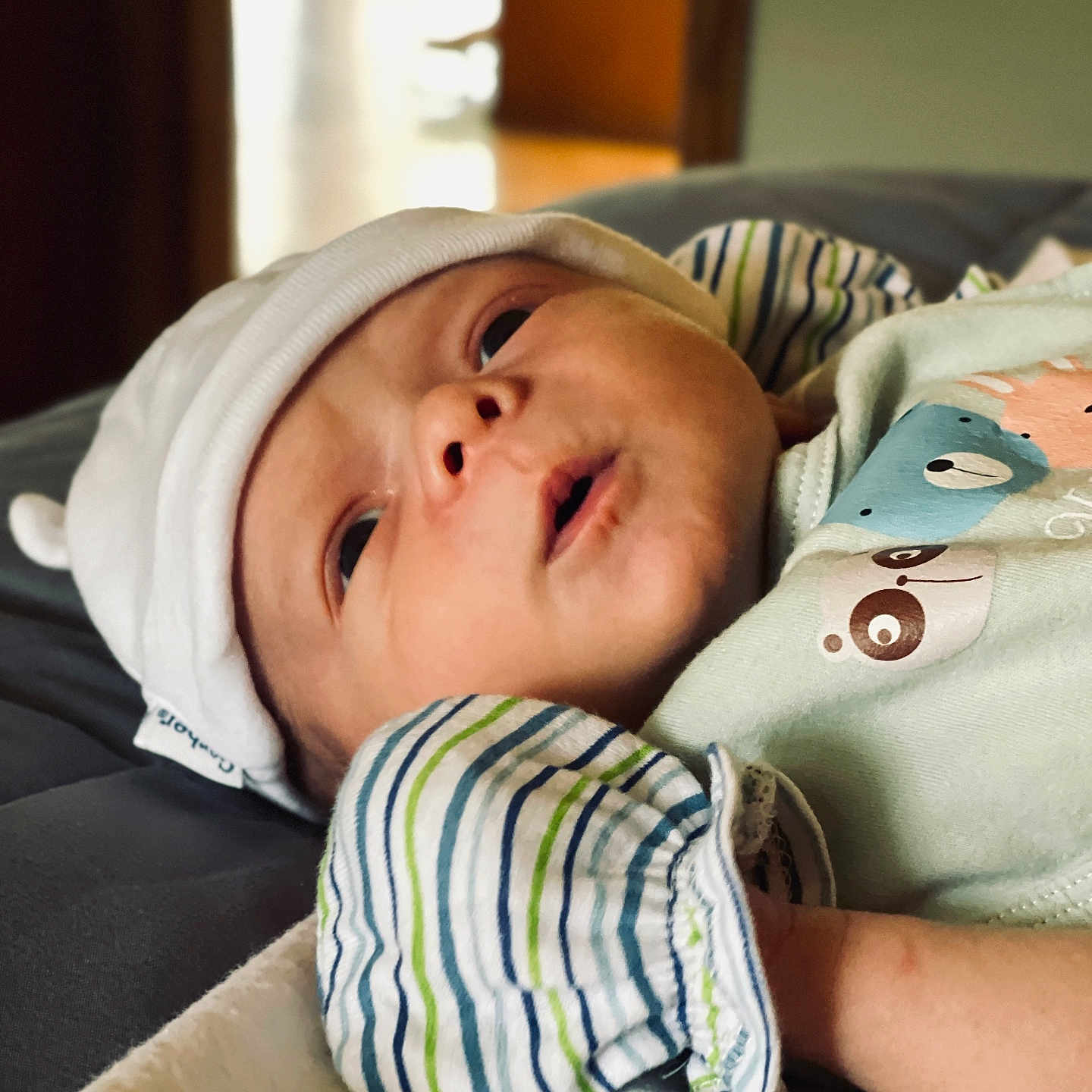 Enzo joined the competition — help win amazing prizes! apparel, baby, blanket, child, closeup, cute, expression, face, hat, headwear, indoors, infant, lying_down, newborn, person, portrait, skin, sleepwear, soft_lighting, striped_clothing