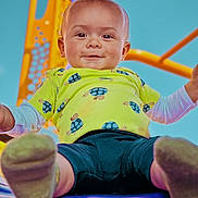 Enzo is registered to the contest to win money with this photo: baby, child, smiling, playground, slide, outdoor, blue_sky, green_shirt, turtle_print, shorts, happy, fun, feet, closeup, person, cute, play, summer, daylight, park