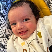 Swan participe au concours pour gagner de l'argent avec cette photo : baby, smiling, infant, face, eyes, clothing, white_outfit, curly_hair, patterned_cushion, yellow_background, cute, happy, portrait, closeup, child, skin, cheeks, lying_down, indoor, cozy