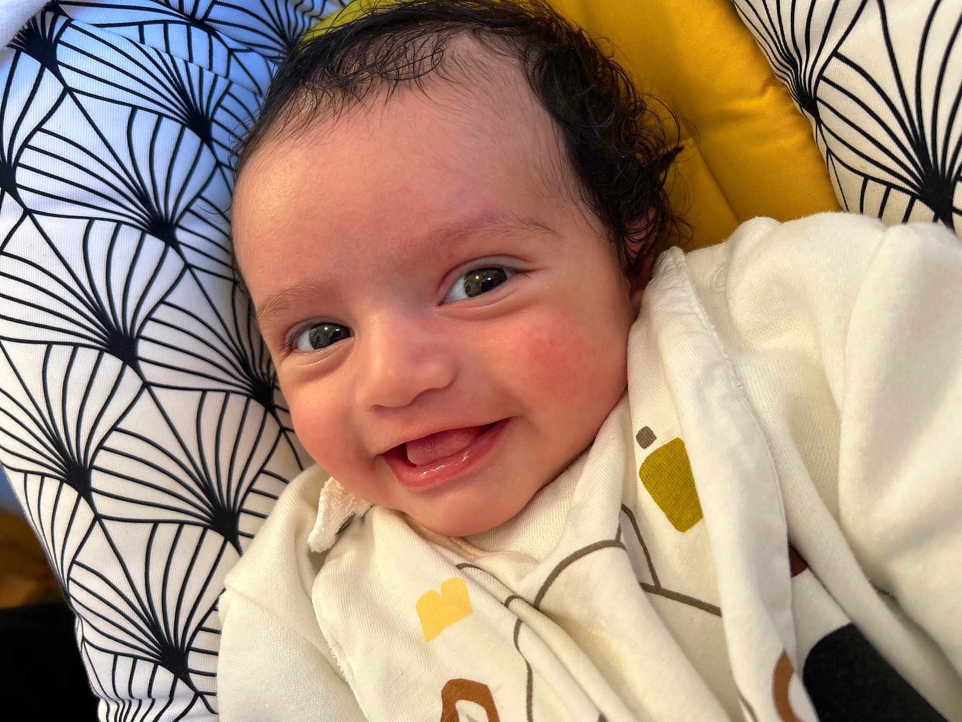 Swan participe au concours pour gagner de l'argent avec cette photo : baby, smiling, infant, face, eyes, clothing, white_outfit, curly_hair, patterned_cushion, yellow_background, cute, happy, portrait, closeup, child, skin, cheeks, lying_down, indoor, cozy