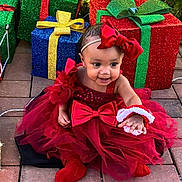 Sariyah joined the competition — help win amazing prizes! baby, child, red_dress, headband, bow, christmas, presents, gift_boxes, holiday_lights, smile, happy, outdoor, brick_patio, festive, tulle_skirt, red_booties, celebration, cute, person, portrait