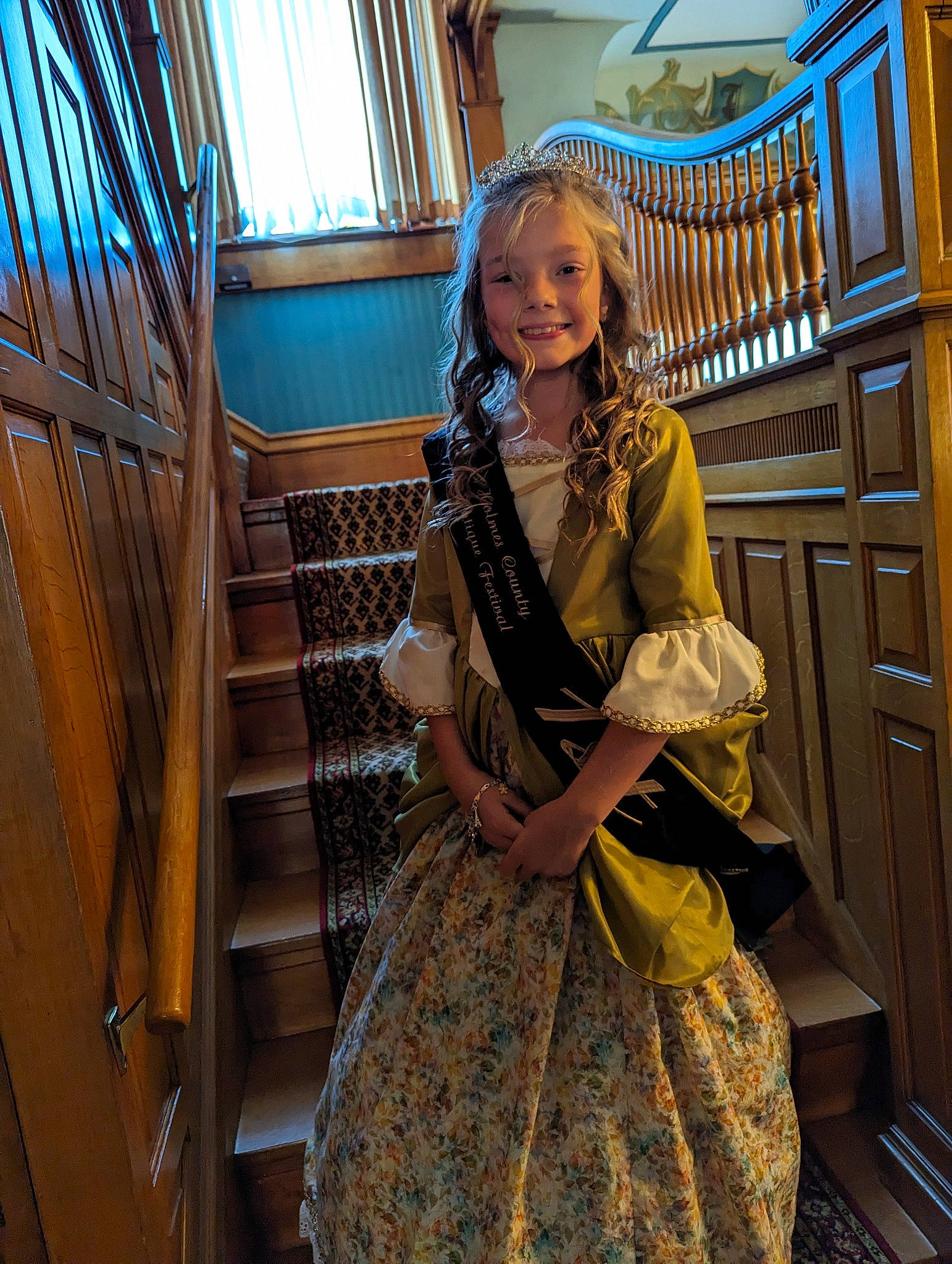 Audrey is registered to the contest to win money with this photo: blond, blue, day_dress, electric_blue, event, fashion_design, formal_wear, fun, handrail, joy, leisure, long_hair, one_piece_garment, pattern, person, ruffle, sitting, smile, stairs, textile