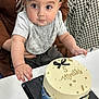 Habeebullah joined the competition — help win amazing prizes! baby, child, cake, table, bib, cap, celebration, food, dessert, mustache, gold_beads, gray_clothing, brown_chair, patterned_background, drool, hand, face, eyes, sitting, indoor