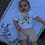 Habeebullah is registered to the contest to win money with this photo: baby, smiling, child, blanket, embroidery, floral_pattern, carpet, tshirt, shorts, barefoot, indoor, happy, lying_down, person, infant, cute, fabric, pattern, text_on_clothing, casual_clothing