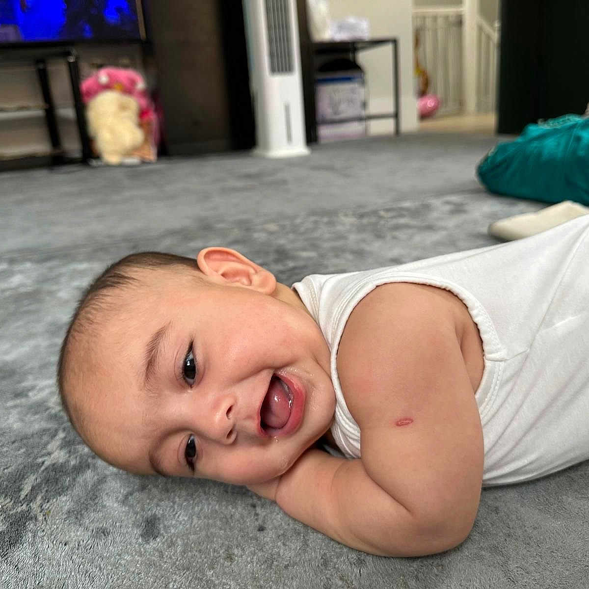 Habeebullah joined the competition — help win amazing prizes! arm, baby, carpet, cheerful, child, closeup, cute, face, floor, head, home, indoor, infant, lying_down, person, relaxed, scratch, smiling, soft_texture, white_clothing