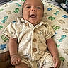 baby, infant, smile, clothing, button, pillow, dinosaur_pattern, hand, bottle, lying_down, cute, happy, indoors, child, portrait, fabric, soft, skin, person, baby_outfit