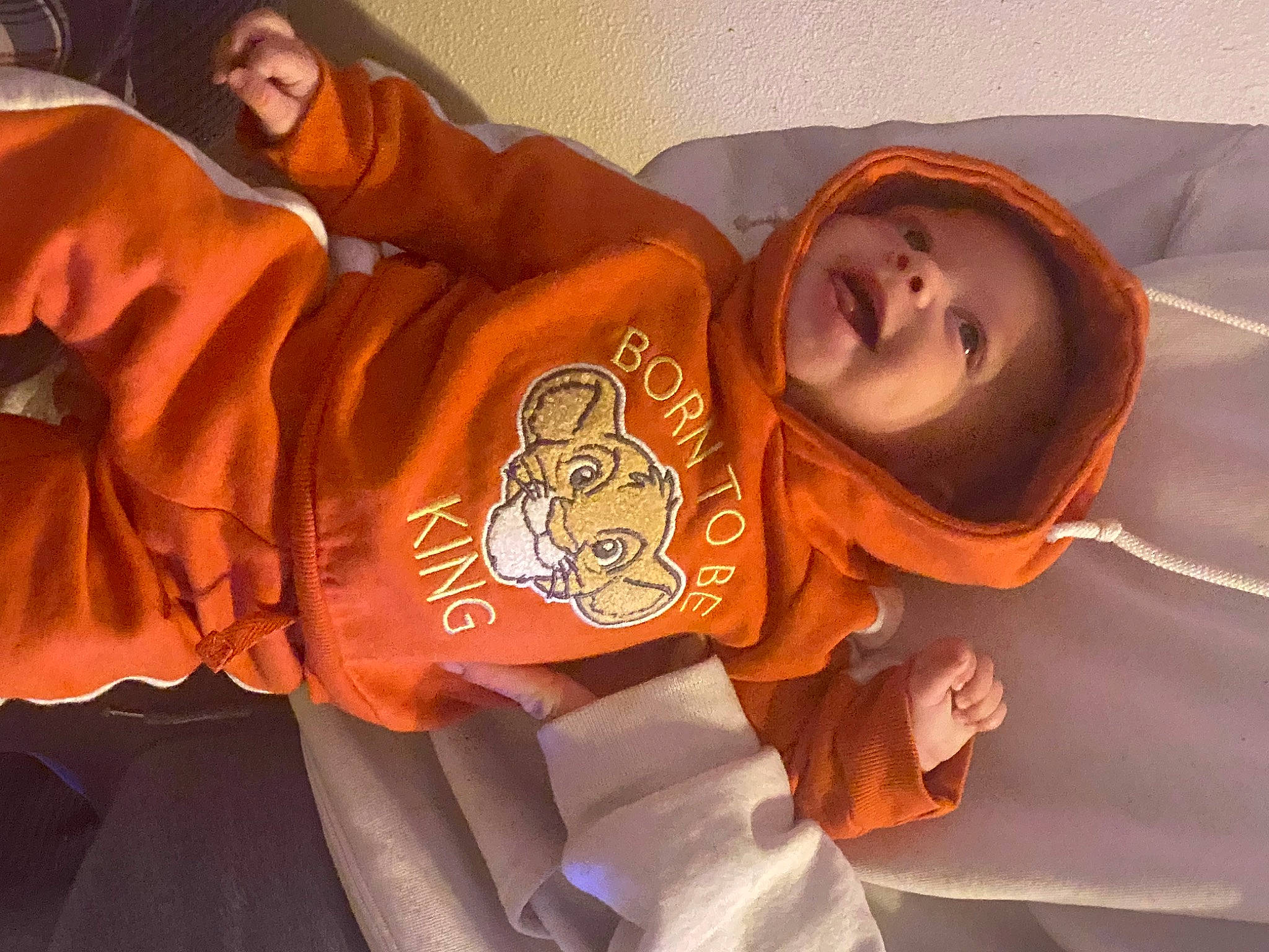 Jaxon is registered to the contest to win money with this photo: child, comfort, elbow, flesh, fun, happy, headgear, headwear, orange, person, room, sitting, sleeve, smile, t_shirt, wood, wrist
