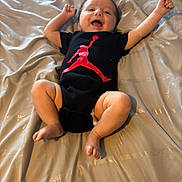 Kash joined the competition — help win amazing prizes! baby, infant, smile, happy, onesie, clothing, bed, bedding, fabric, person, cute, child, skin, arms, legs, foot, head, indoors, joy, lying_down