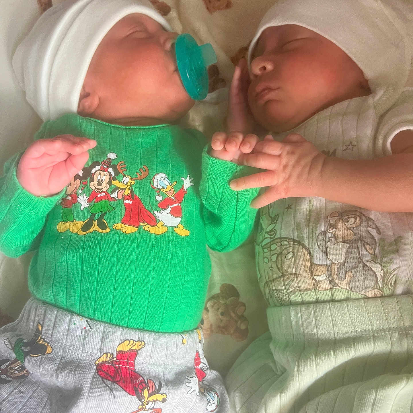 Jayden And Aiden is registered to the contest to win money with this photo: baby, bed, cartoon_clothing, child, cozy, cute, green_sweater, hand_holding, hat, indoors, infant, newborn, pacifier, peaceful, portrait, sleeping, soft_lighting, striped_pants, teddy_bear_blanket, two_babies