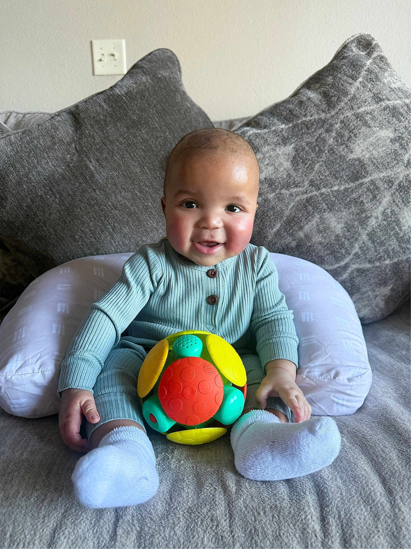 Reshard is registered to the contest to win money with this photo: baby, child, smiling, toy, couch, pillow, socks, indoor, happy, infant, person, clothing, face, cute, seated, home, play, colorful, comfortable, portrait