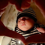 Muhammad Zaviyar is registered to the contest to win money with this photo: baby, sleeping, infant, striped_clothing, hat, hands, heart_shape, closeup, peaceful, soft_lighting, indoor, portrait, cute, toddler, newborn, child, cozy, warm, skin, face