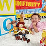 Madison joined the competition — help win amazing prizes! child, toddler, toy_story, woody, jessie, bullseye, mr_potato_head, plush_toys, colorful_blocks, white_rug, birthday_backdrop, smiling, curly_hair, pink_clothing, indoor, playful, decorations, portrait, happy, fun