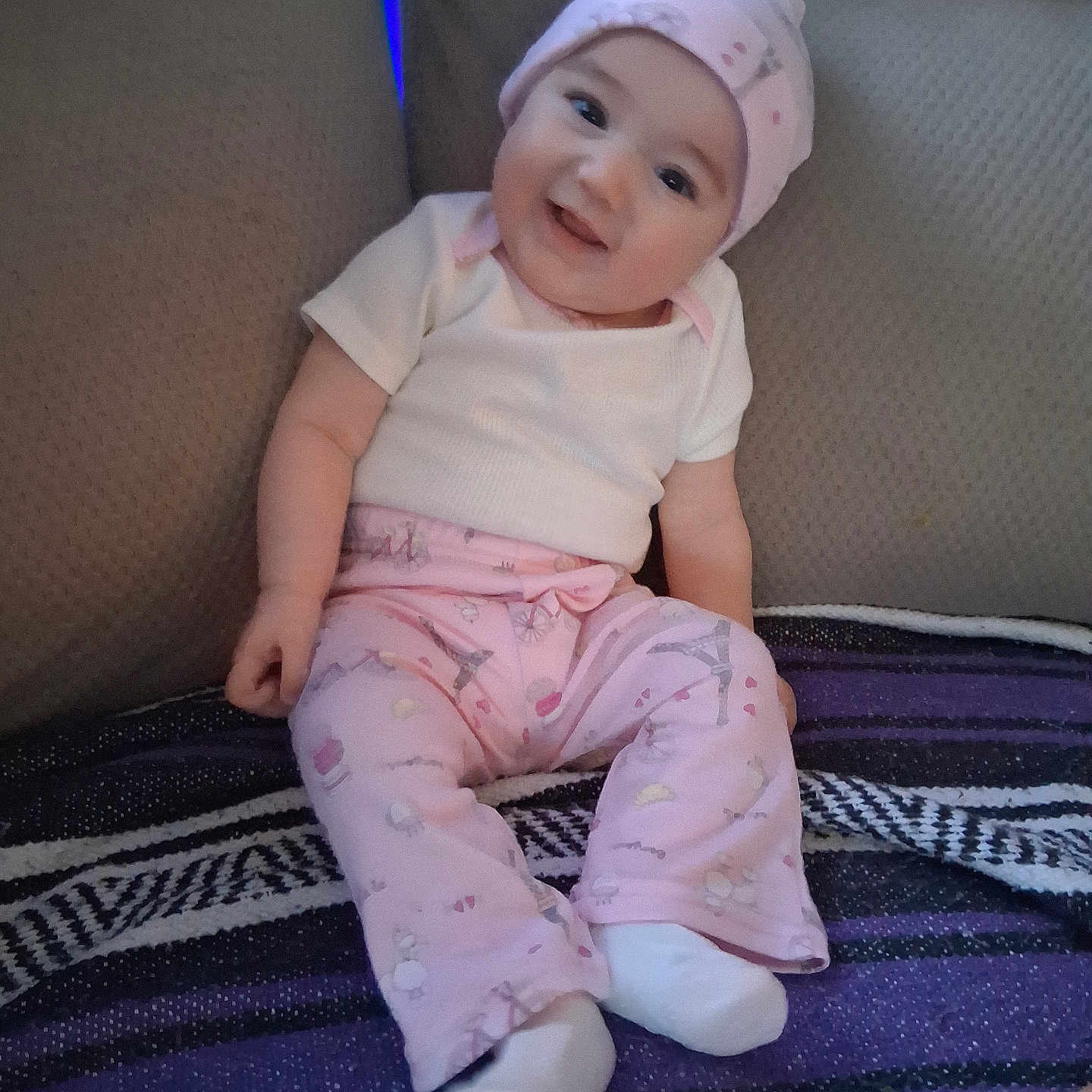 Harvest joined the competition — help win amazing prizes! baby, blanket, casual_clothing, child, couch, cozy, face, furniture, happy, head, indoor, infant, onesie, patterned_blanket, pink_hat, pink_pants, portrait, sitting, smiling, socks