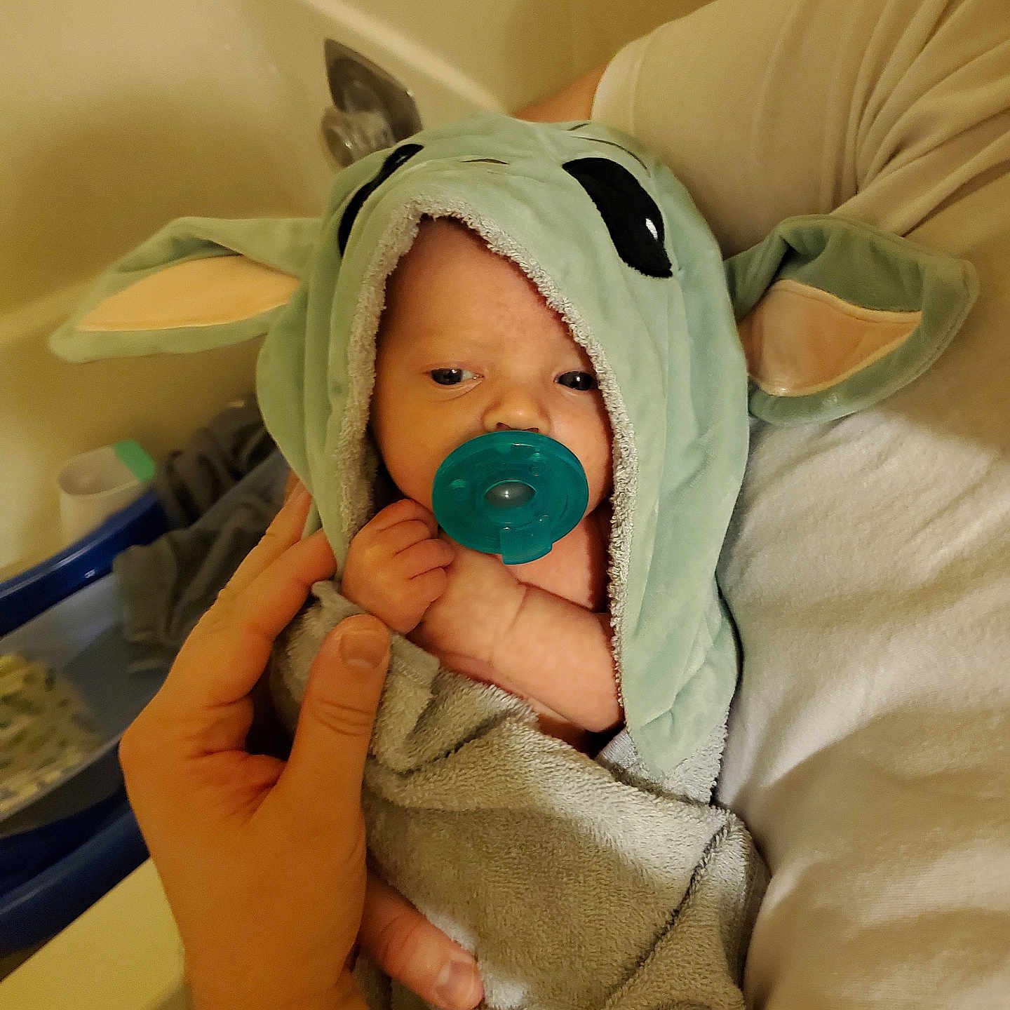 Theo is registered to the contest to win money with this photo: baby, blanket, bodypart, bonnet, clothing, crib, face, finger, furniture, hand, hat, head, hood, hoodie, infantbed, knitwear, newborn, person, sweater, sweatshirt