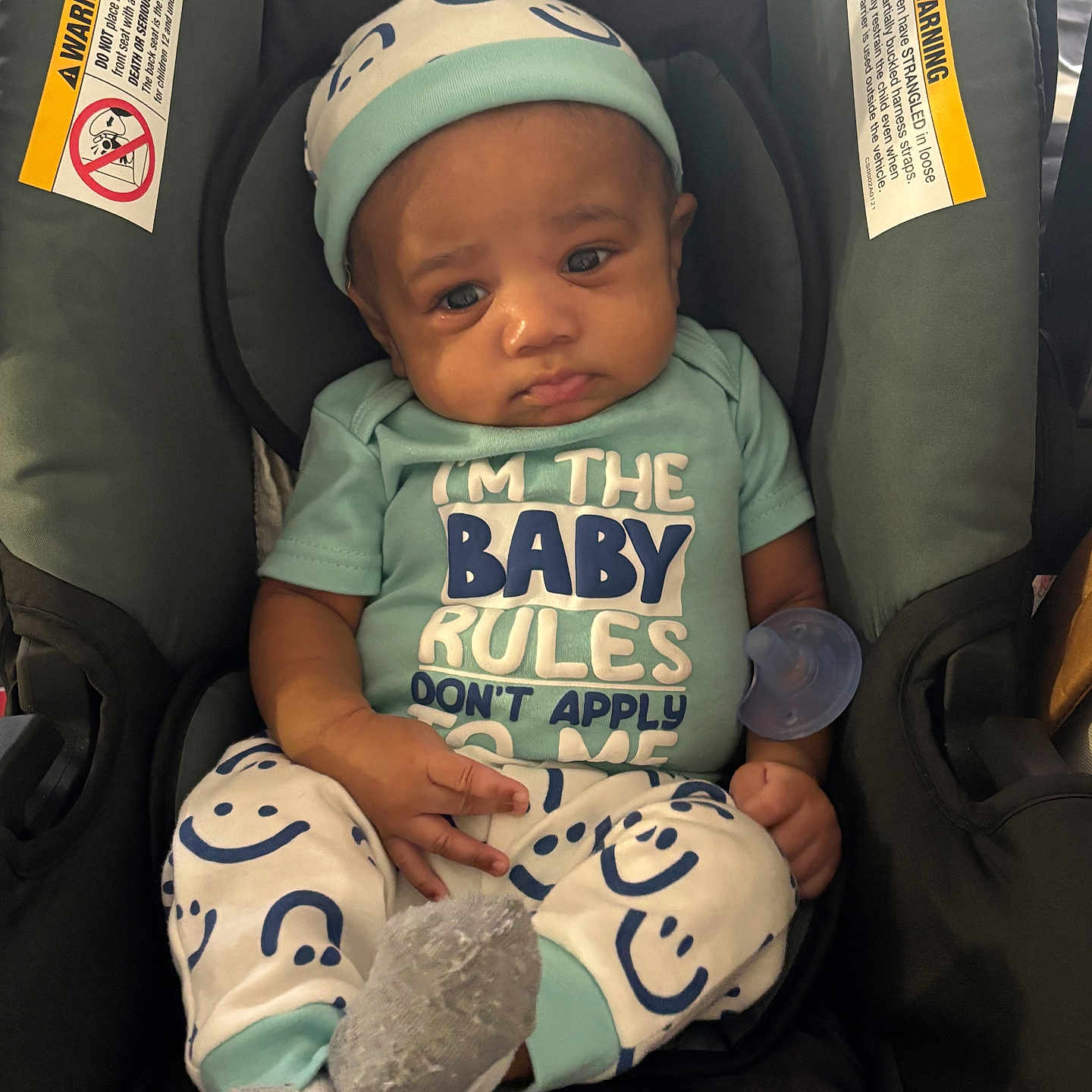 Dezyrion is registered to the contest to win money with this photo: baby, car_seat, infant, clothing, hat, pacifier, socks, person, face, expression, seated, comfort, smiley_faces, child, casual, indoor, cute, young, portrait, apparel