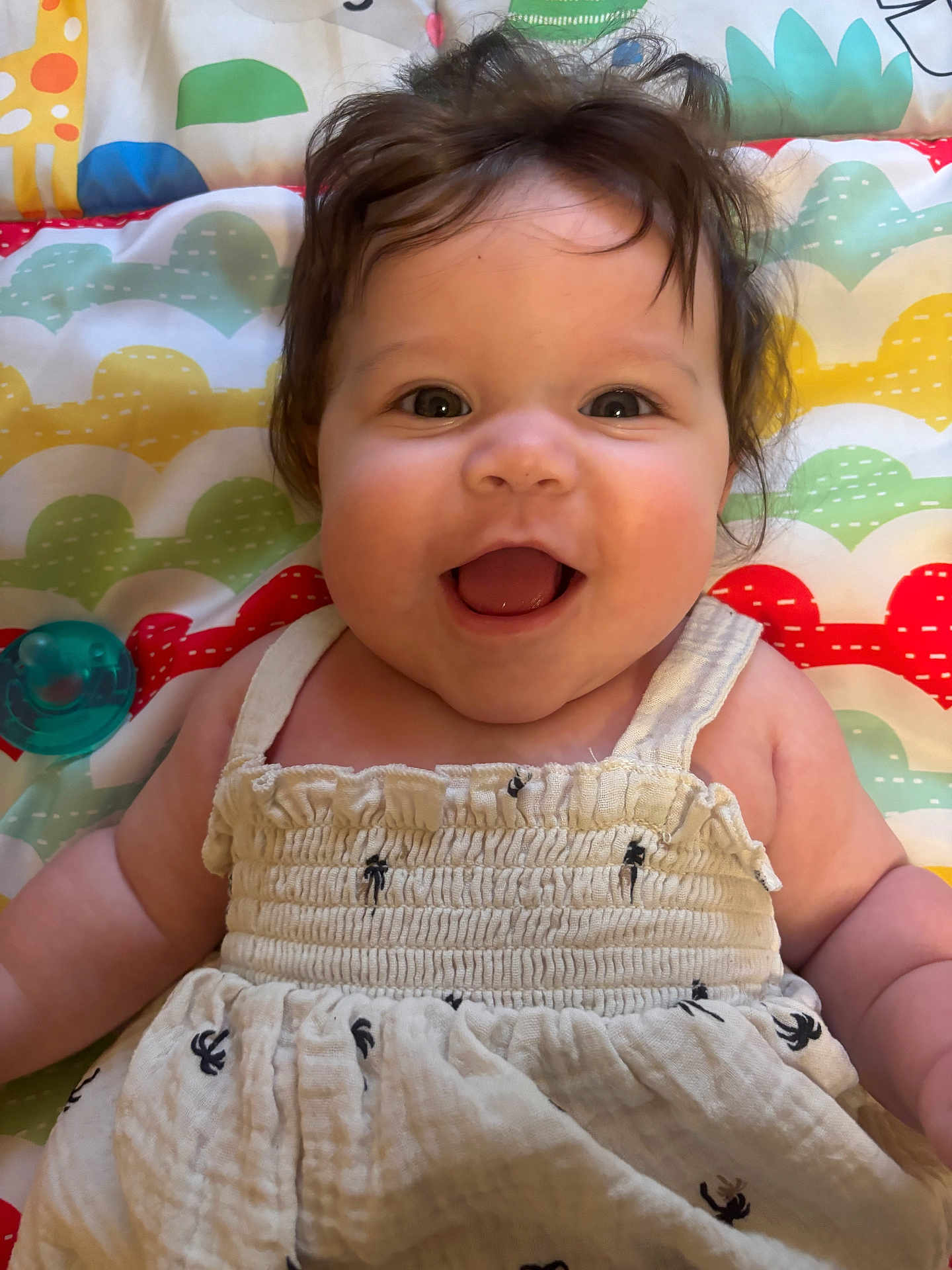 Elena joined the competition — help win amazing prizes! baby, smiling, happy, infant, child, face, hair, eyes, clothing, dress, patterned_blanket, colorful, cute, portrait, laying_down, skin, cheeks, pacifier, indoor, closeup