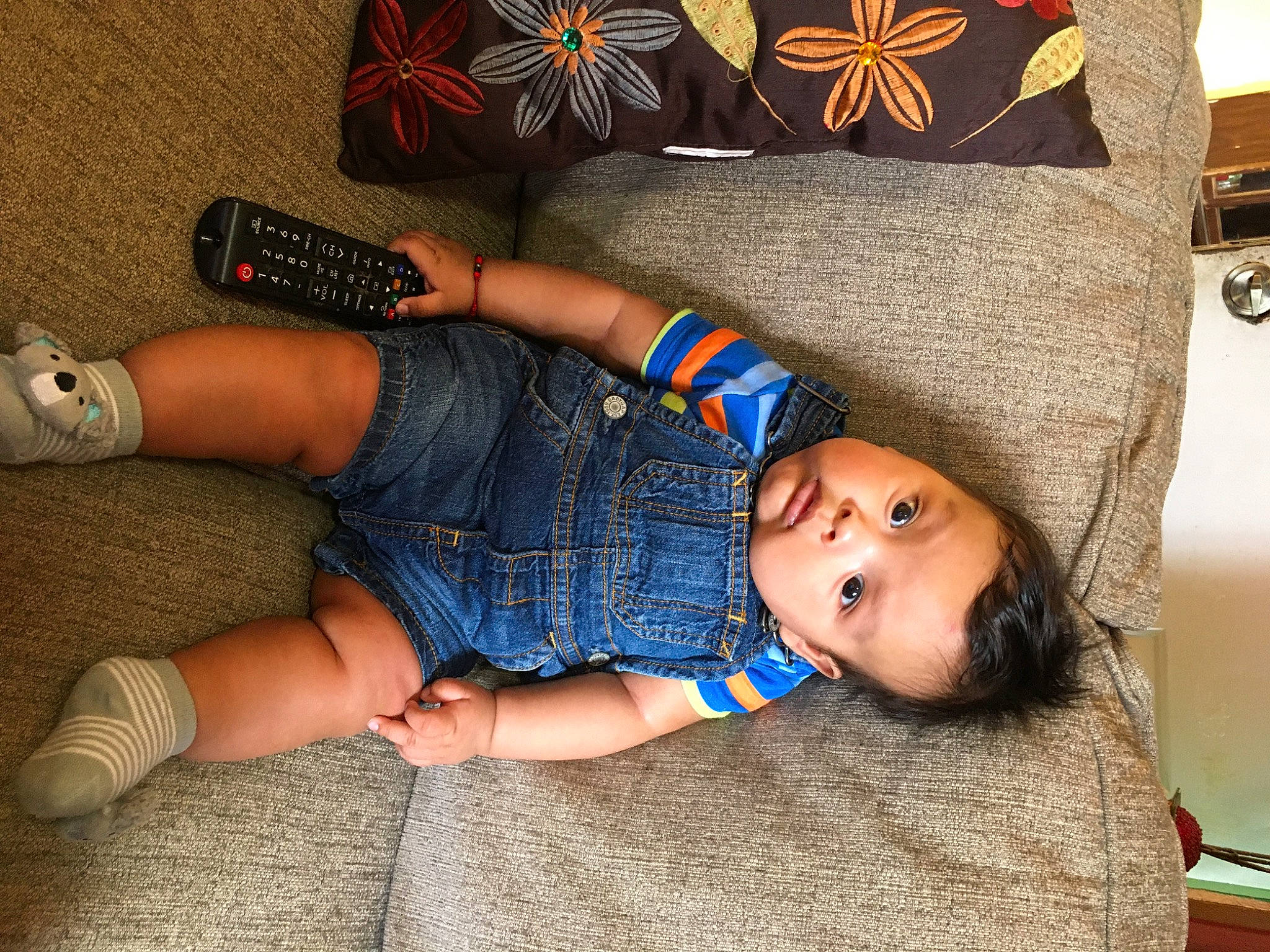 Enrique is registered to the contest to win money with this photo: child, couch, denim, electronic_device, human_leg, jeans, joint, knee, leg, person, shoe, sitting, thigh, toddler, trunk