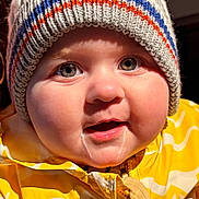 Paul participe au concours pour gagner de l'argent avec cette photo : child, baby, infant, beanie, knit_hat, jacket, yellow, drool, cheeks, close_up, portrait, smiling, eyes, rosy_cheeks, winter_clothing, zipper, hands, candid, indoor, warm_lighting