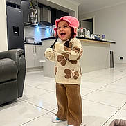 Anubhavi Kaur is registered to the contest to win money with this photo: toddler, child, indoor, kitchen, smiling, laughing, hat, pink, sweater, butterfly, pants, brown, white_shoes, tile_floor, furniture, refrigerator, cabinet, counter, blanket, happy
