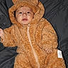 baby, infant, child, costume, bear_suit, fluffy, cute, portrait, indoor, clothing, face, expression, hand, foot, sleepwear, soft, warm, quilted_background, zipped, hood