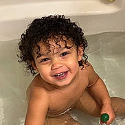 Milo is registered to the contest to win money with this photo: toddler, child, bath, bathtub, water, curly_hair, smiling, happy, playing, toy, skin, indoors, cute, sitting, young_child, person, bathroom, wet, fun, childhood