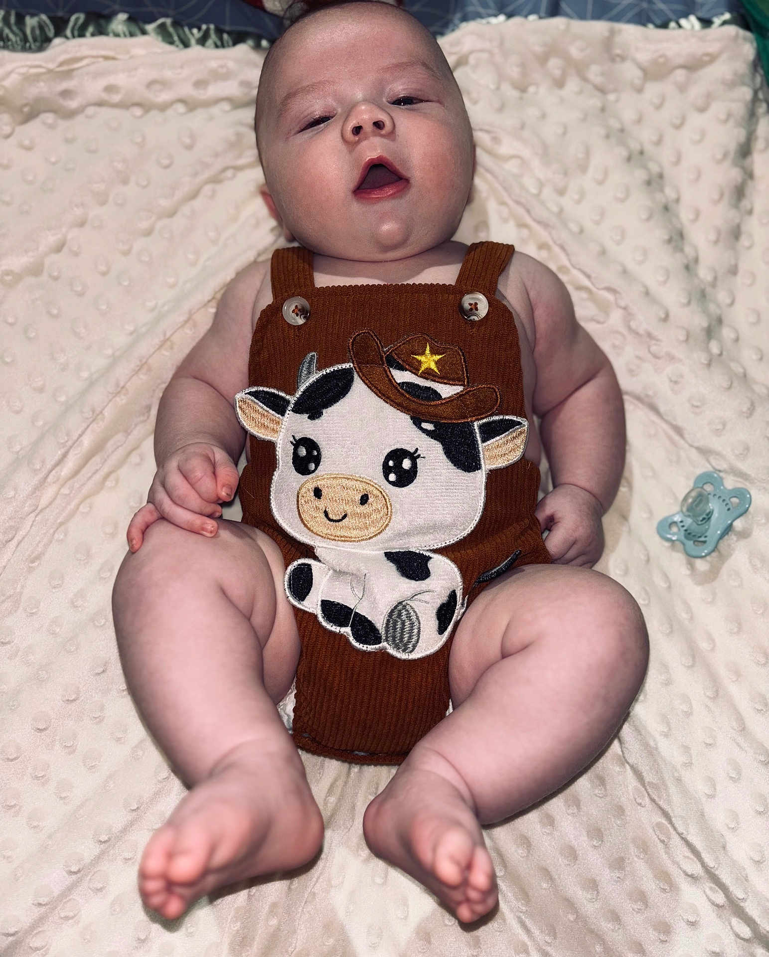 Colton joined the competition — help win amazing prizes! baby, infant, romper, cowboy_cow_patch, blanket, pacifier, cute, chubby, soft_texture, lying_down, clothing, skin, foot, hand, face, expression, indoor, child, adorable, sleepwear