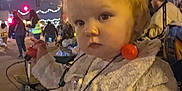 Krysleine is registered to the contest to win money with this photo: toddler, child, nighttime, outdoor, festival, lights, street, people, costume, sparkly_clothing, necklace, holiday, curious, portrait, winter, festive, crowd, trees, urban, celebration