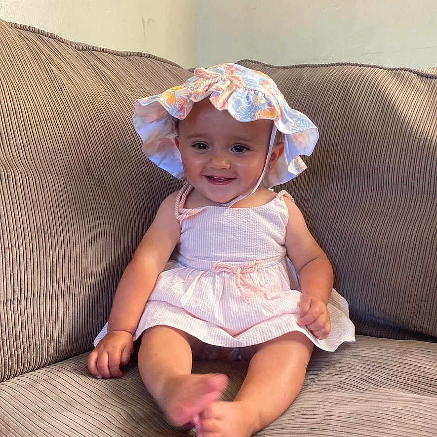 Macey May is registered to the contest to win money with this photo: apparel, baby, child, couch, cute, dress, face, foot, furniture, hand, happy, hat, headwear, indoor, infant, person, sitting, skin, smiling, young
