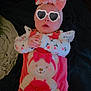 baby, bear_applique, bedding, big_bow, blanket, child_clothing, cozy, cute, floral_shirt, hands_together, headband, heart_sunglasses, indoor, infant, lying_on_back, pink_overalls, portrait, sticker_glasses, timestamp_text, toddler