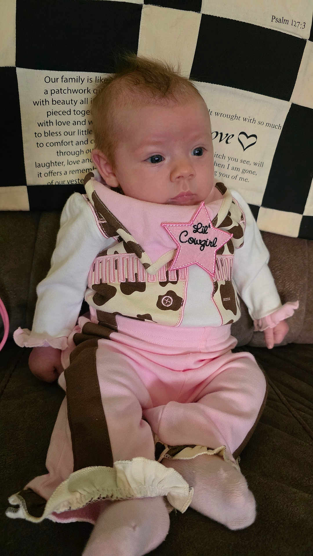 Kelly joined the competition — help win amazing prizes! baby, infant, child, pink_clothing, brown_clothing, cowgirl_outfit, star_patch, sitting, couch, quilt, patchwork, text, face, hands, feet, sock, indoor, portrait, cute, curious