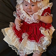 Kelly joined the competition — help win amazing prizes! baby, infant, child, dress, lace, red_clothing, white_socks, cute, portrait, indoors, fabric, costume, adorable, laying_down, young_child, hands, feet, headwear, soft_texture, curious