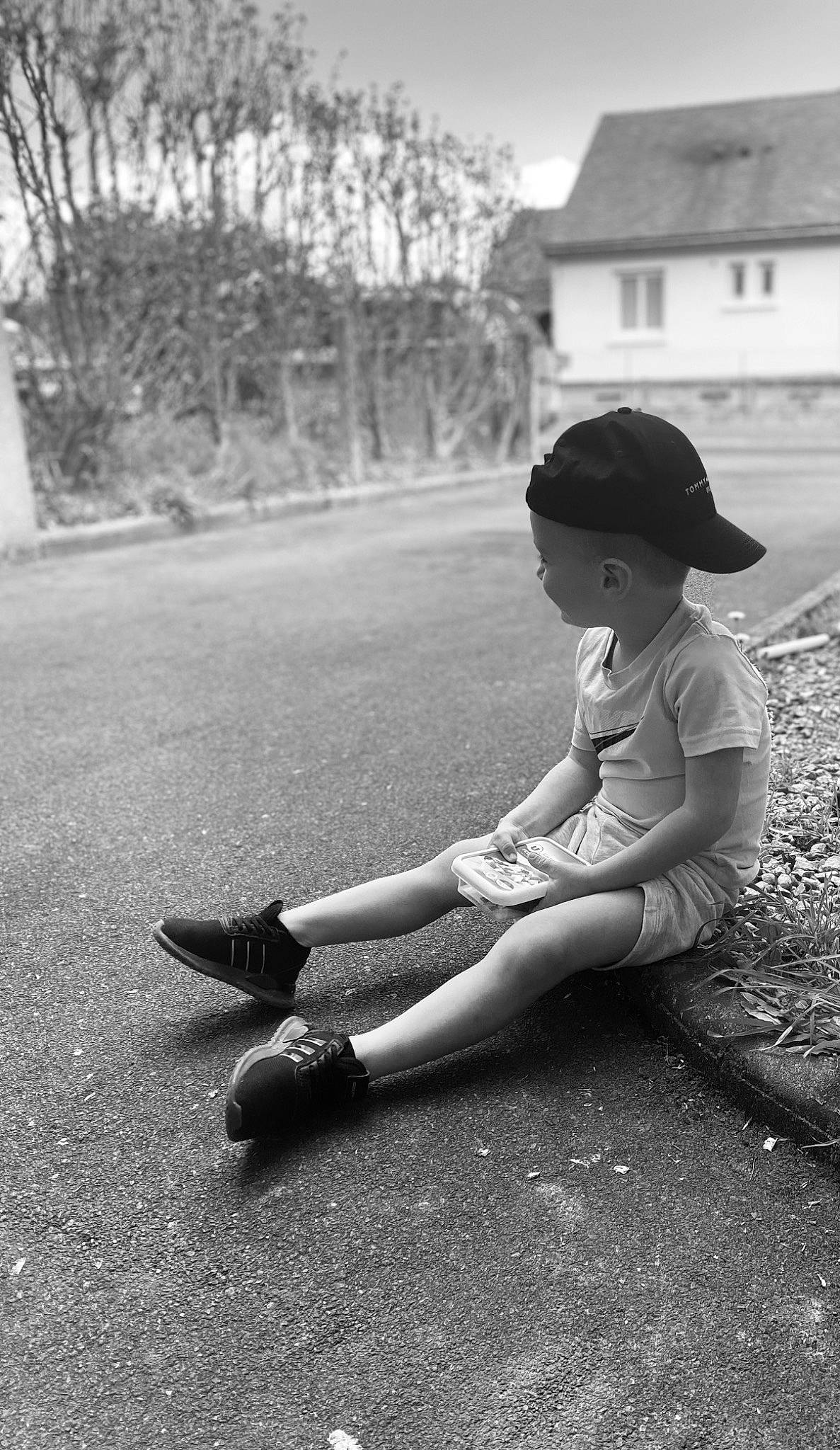 Lyam participe au concours pour gagner de l'argent avec cette photo : asphalt, black, black_and_white, flash_photography, footwear, grass, hat, knee, leg, people_in_nature, person, plant, road, road_surface, shoe, sidewalk, sky, style, tints_and_shades, toddler