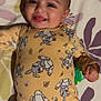Athena is registered to the contest to win money with this photo: baby, infant, smiling, happy, moawk_hairstyle, yellow_onesie, cartoon_bunny, toy, lying_down, bedspread, floral_pattern, cute, child, portrait, indoor, playful, young_child, human, face, expression