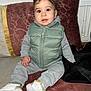 toddler, child, sitting, indoor, clothing, vest, sneakers, couch, pillow, face, person, cute, young_child, casual_wear, footwear, expression, portrait, home, cozy, curious