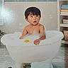 Mateo is registered to the contest to win money with this photo: bath, bathroom, bathtub, black_hair, bubbles, child, curious, family, home, indoor, portrait, rubber_duck, shelf, sitting, surprised, tile, toddler, towels, water, wet